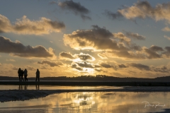 Personnes admirant le soleil couchant sur la jetée d'Arès
